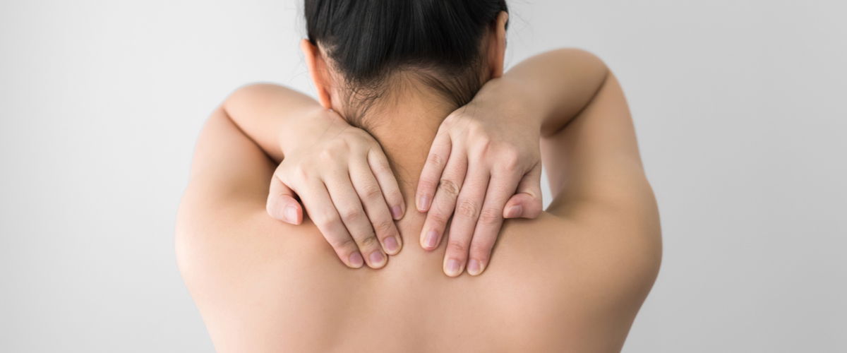 Frau von hinten greift sich in den Nacken