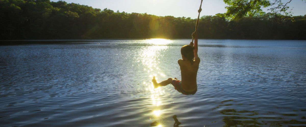 Junge springt an Seil in See