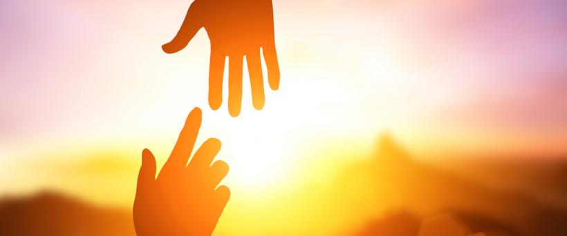 Hände reichen im Sonnenuntergang