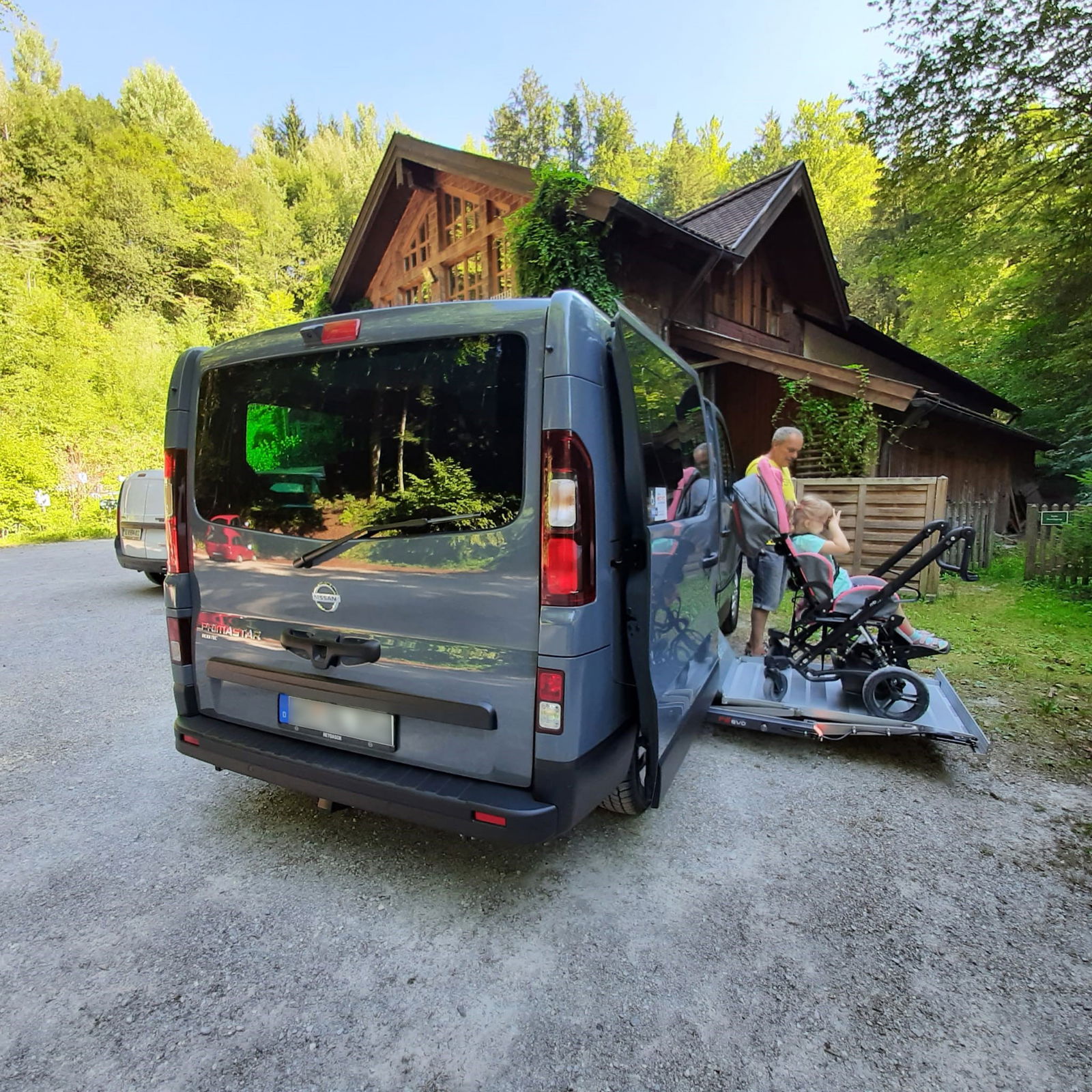 Van mit Minilift auf dem ein Mädchen im Rollstuhl mit Vater ist