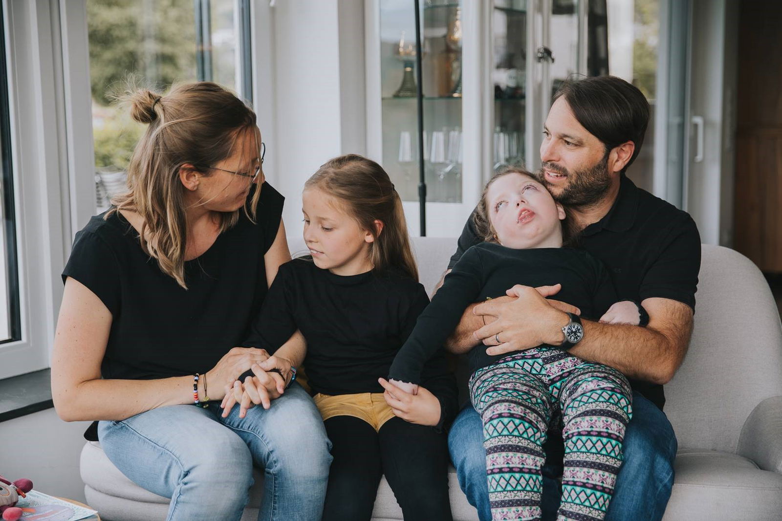 Mutter mit Tochter und Vater mit kranker Tochter im Arm auf dem Sofa