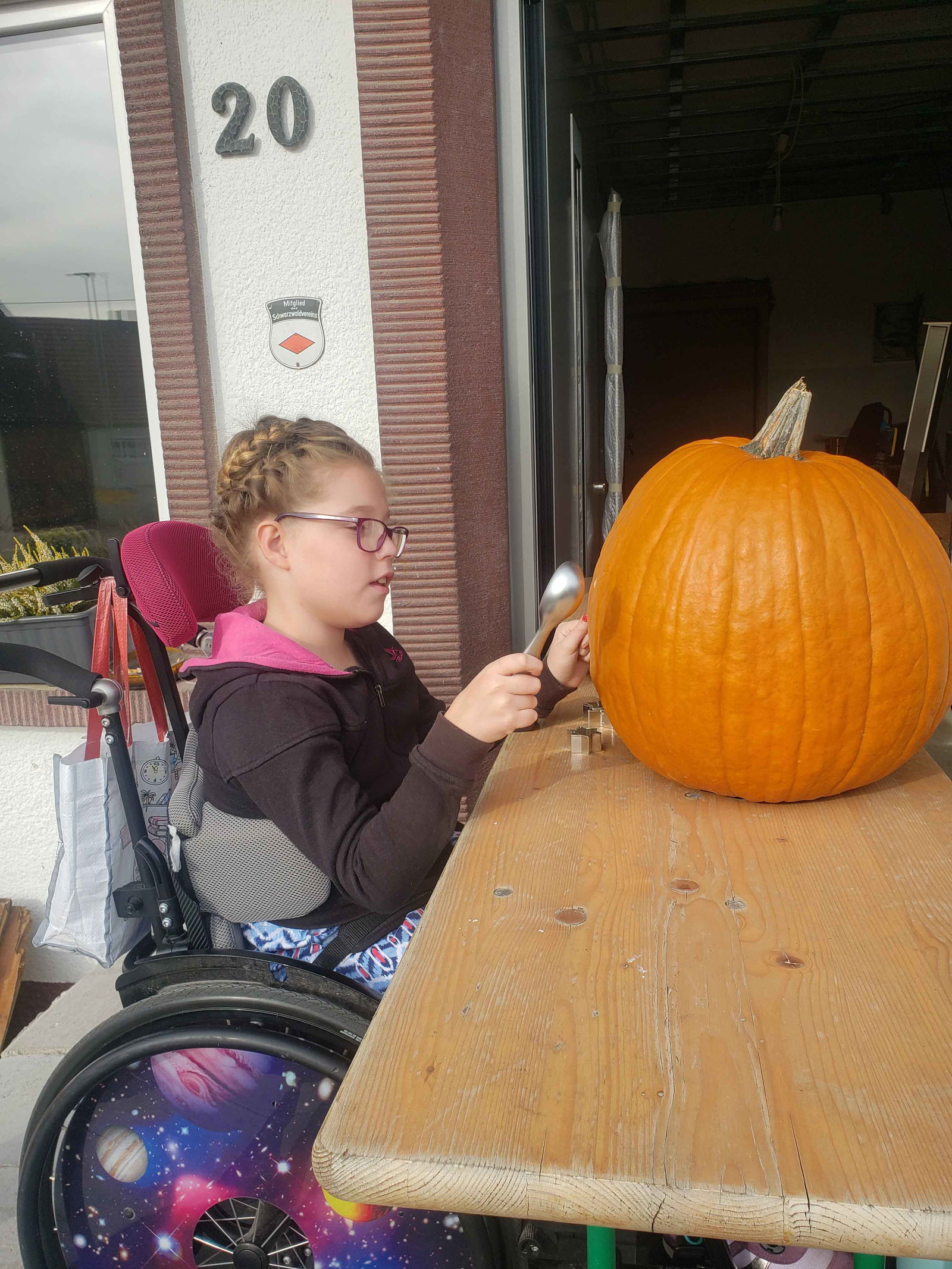 Mädchen im Rollstuhl arbeitet an einem großen Kürbis