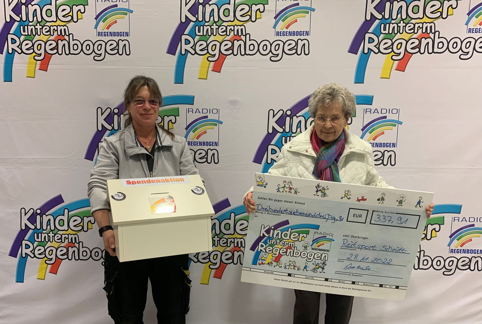 Zwei Frauen mit Spendenscheck für Kinder unterm Regenbogen