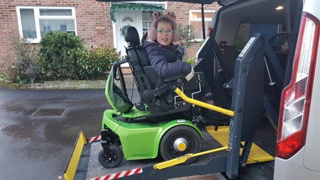 Mädchen in speziellem Rollstuhl auf Minilift am Van