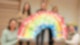 Fünf Frauen halten einen großen gemalten Regenbogen in den Händen