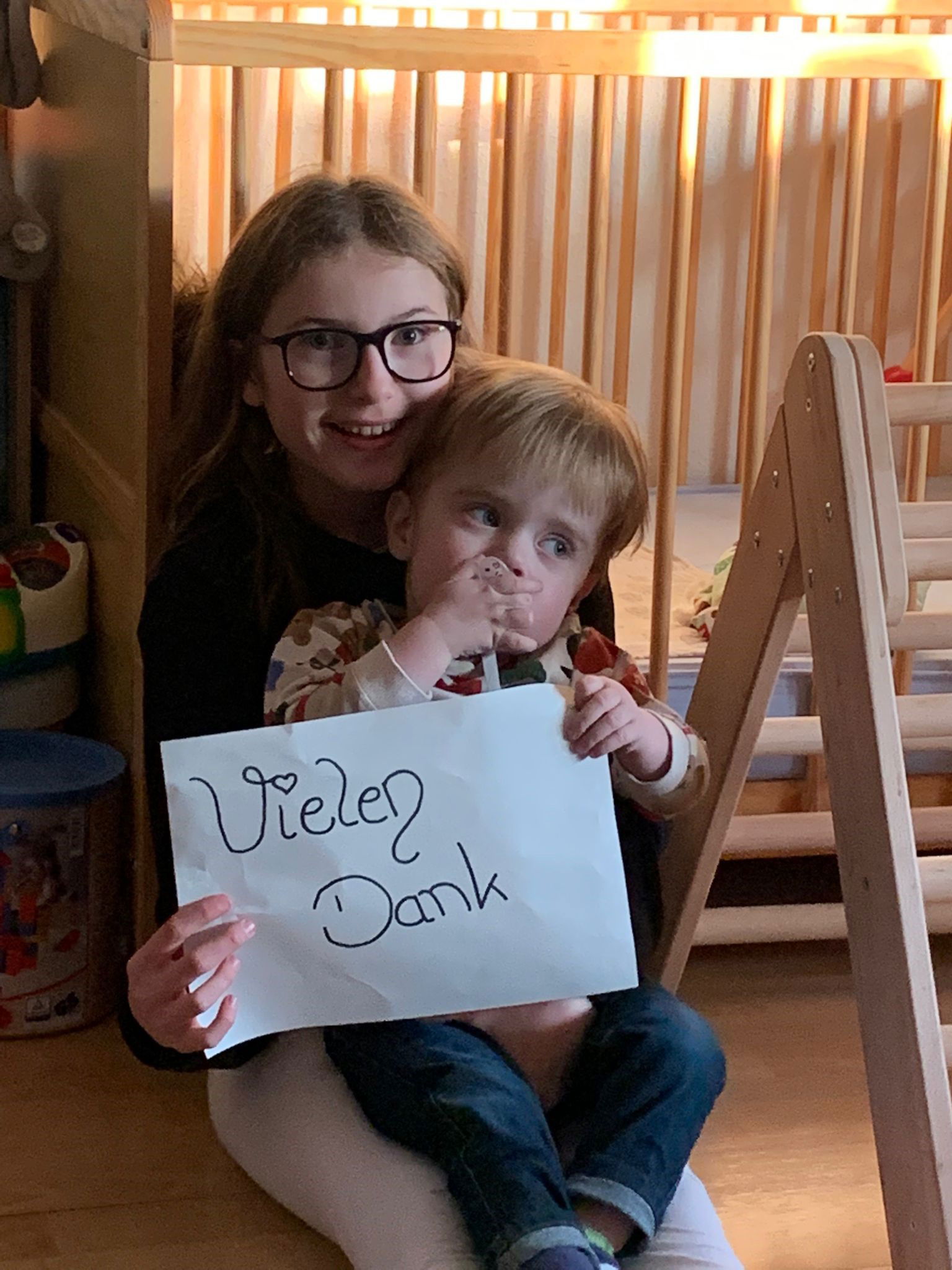 Mädchen und kleiner Junge mit einem Schild auf dem "Vielen Dank" geschrieben steht