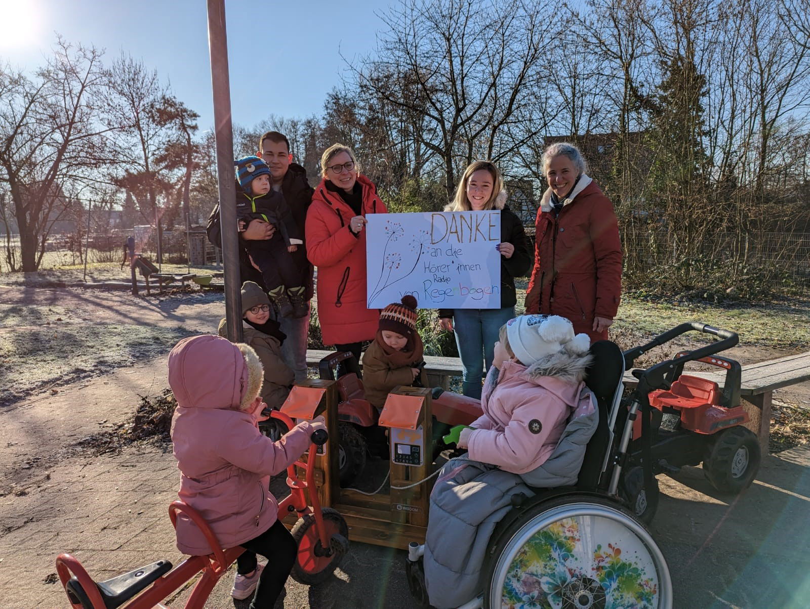 Erwachsene und Kinder mit Kindern im Rollstuhl halten ein Danke-Plakat in den Händen