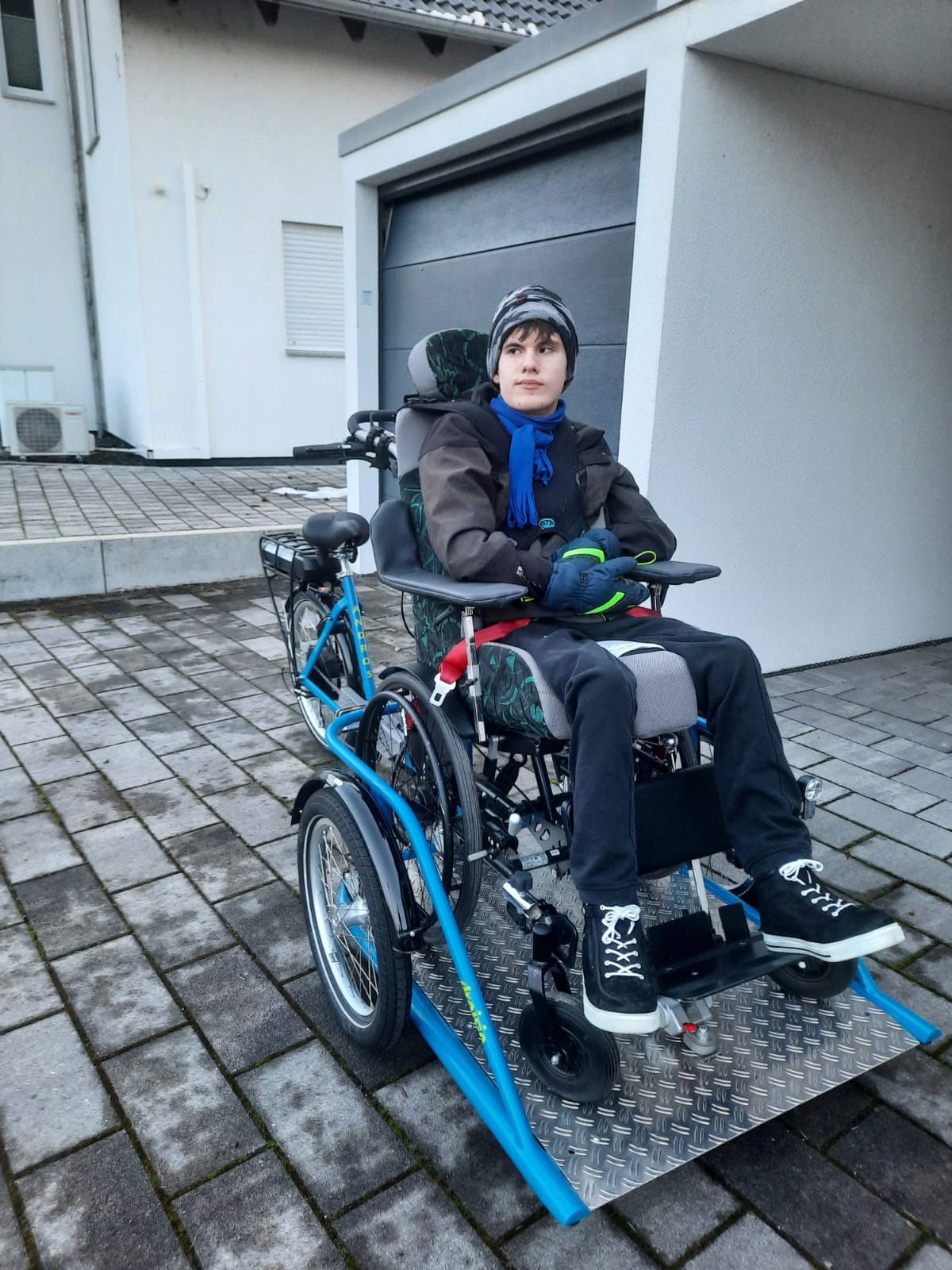 Junge sitzt im Rollsuhl, der auf einem Rehabuggy steht