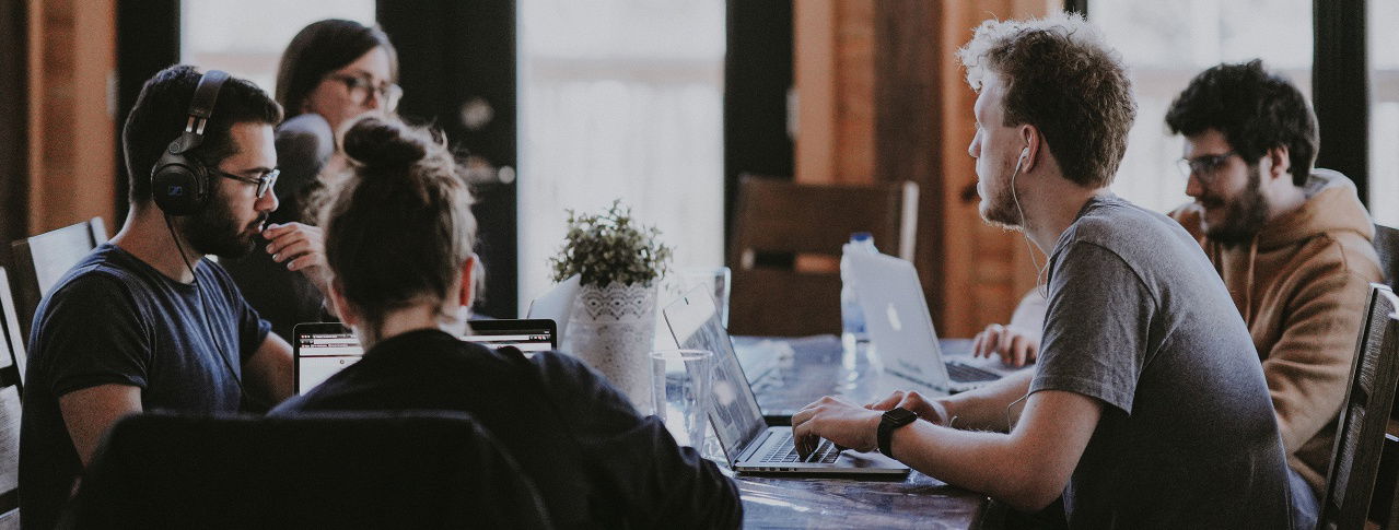 Menschen sitzen am Tisch und arbeiten