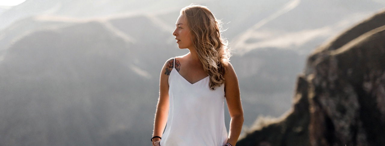 Eine junge Frau steht auf einem Berg und blickt zur Seite 