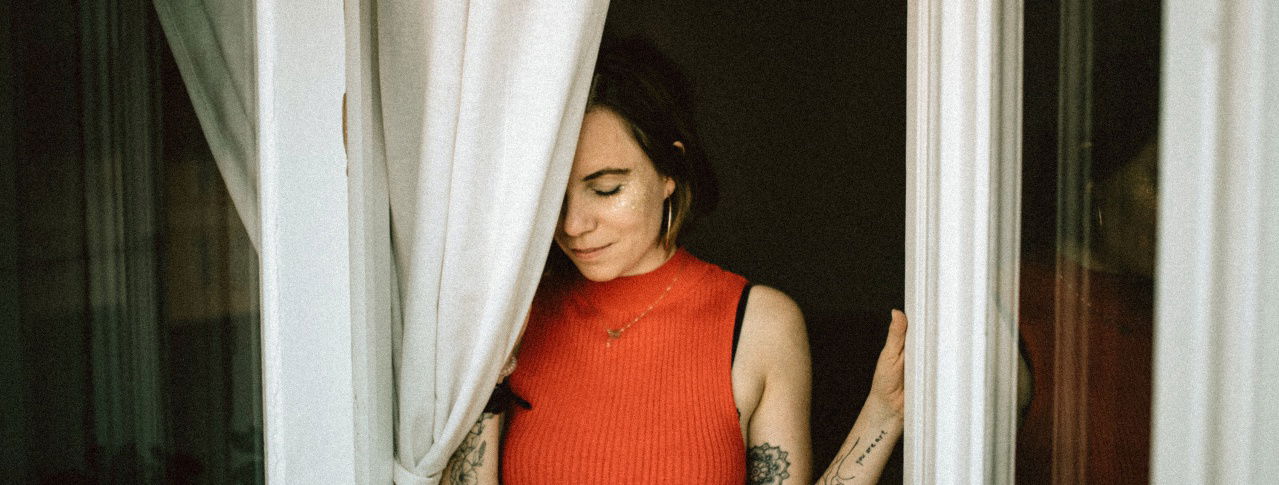 Frau vor Vorhang am Fenster