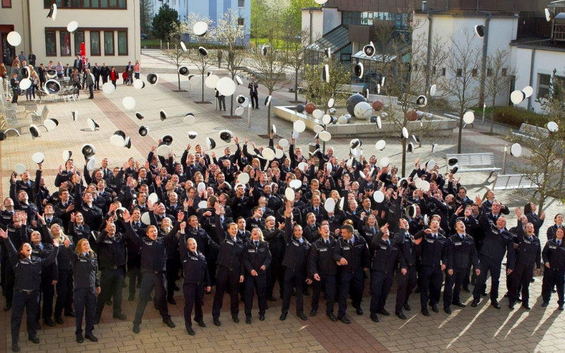 Polizei-Absolventen werfen ihre Mützen in die Luft 