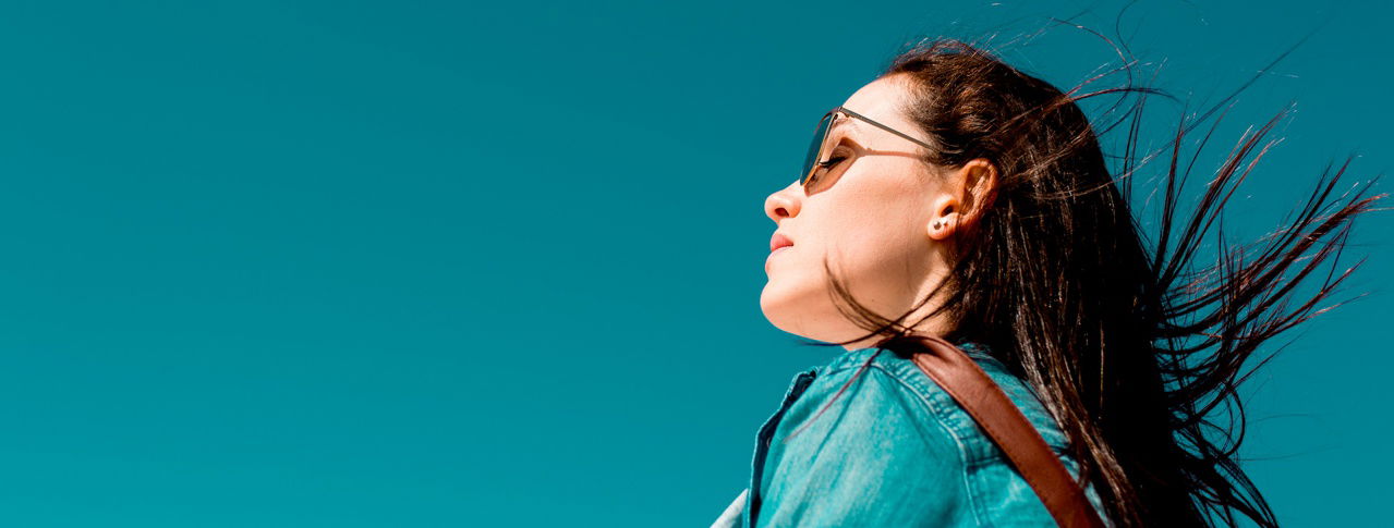 Frau mit Sonnenbrille und türkisfarbenen Hintergrund