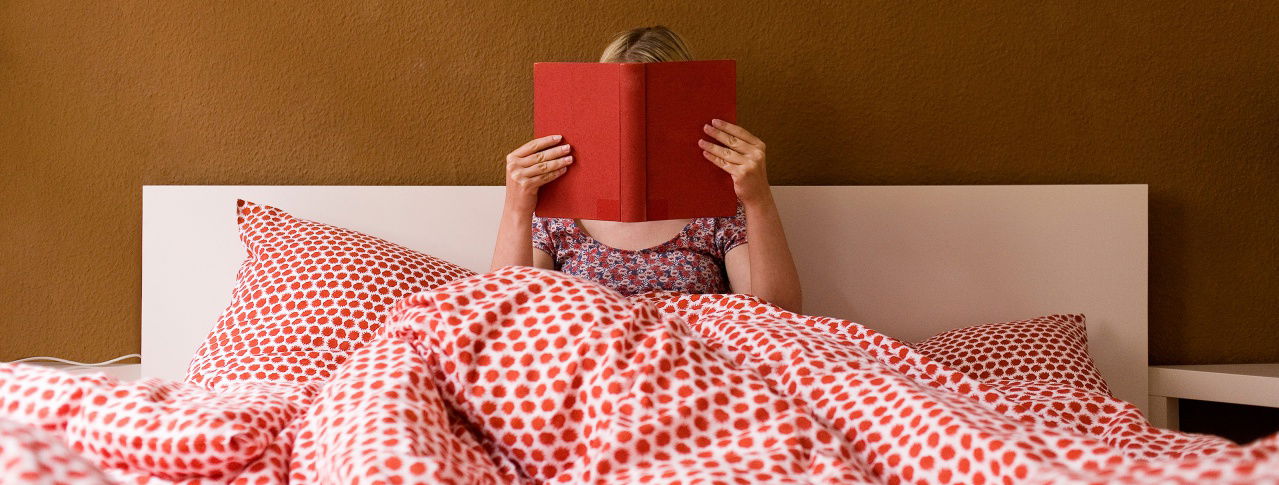 Eine Frau liegt im Bett und liest ein Buch 