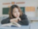 Eine junge Asiatin sitzt nachdenklich in der Schule