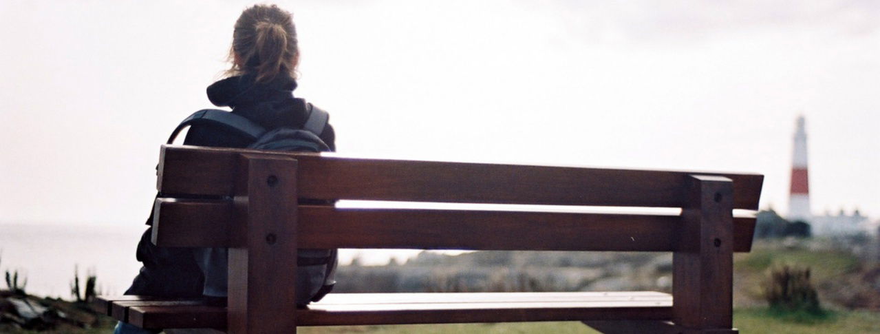 Frau sitzt auf Bank von hinten