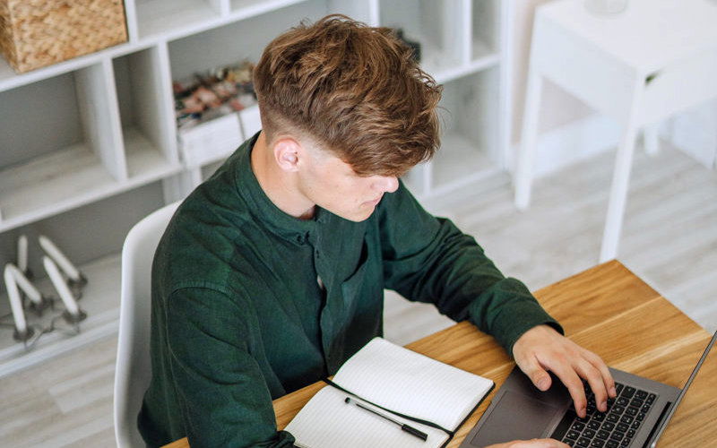 Ein junger Mann schreibt etwas in einen Laptop