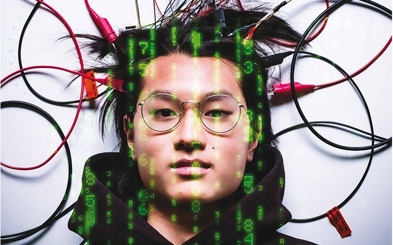 Ein Mann liegt zwischen Kabeln auf dem Boden und wird von Zahlen angestrahlt 