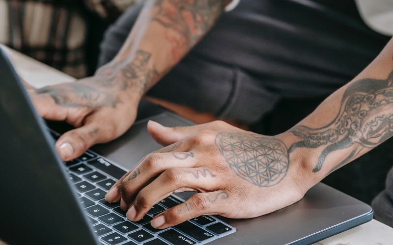 Tätowierte Arme mit Laptop
