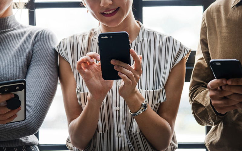 Drei Leute schauen auf Handys 