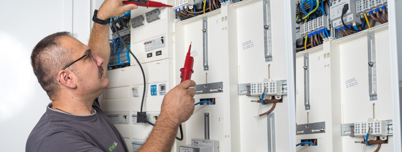 Ein Handwerker der enersol GmbH arbeitet an einem Sicherungskasten 