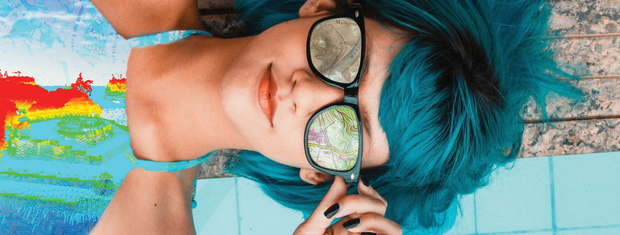 Eine junge Frau liegt auf dem Boden und trägt dabei eine Sonnenbrille und ein Oberteil, das die Erde widerspiegelt 