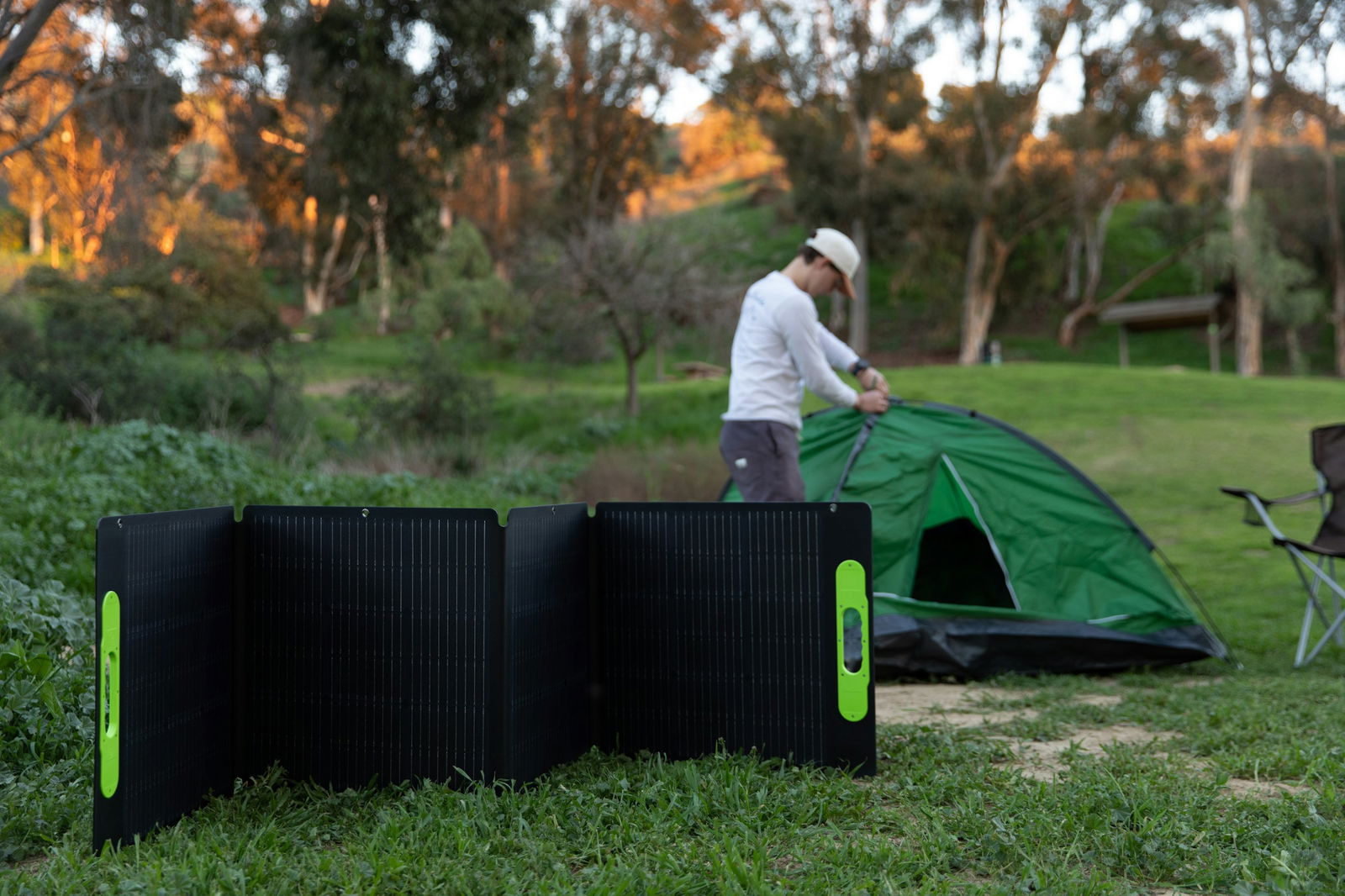 Mann steht neben einem grünen Zelt, im Vordergrund eine mobile Solaranlage