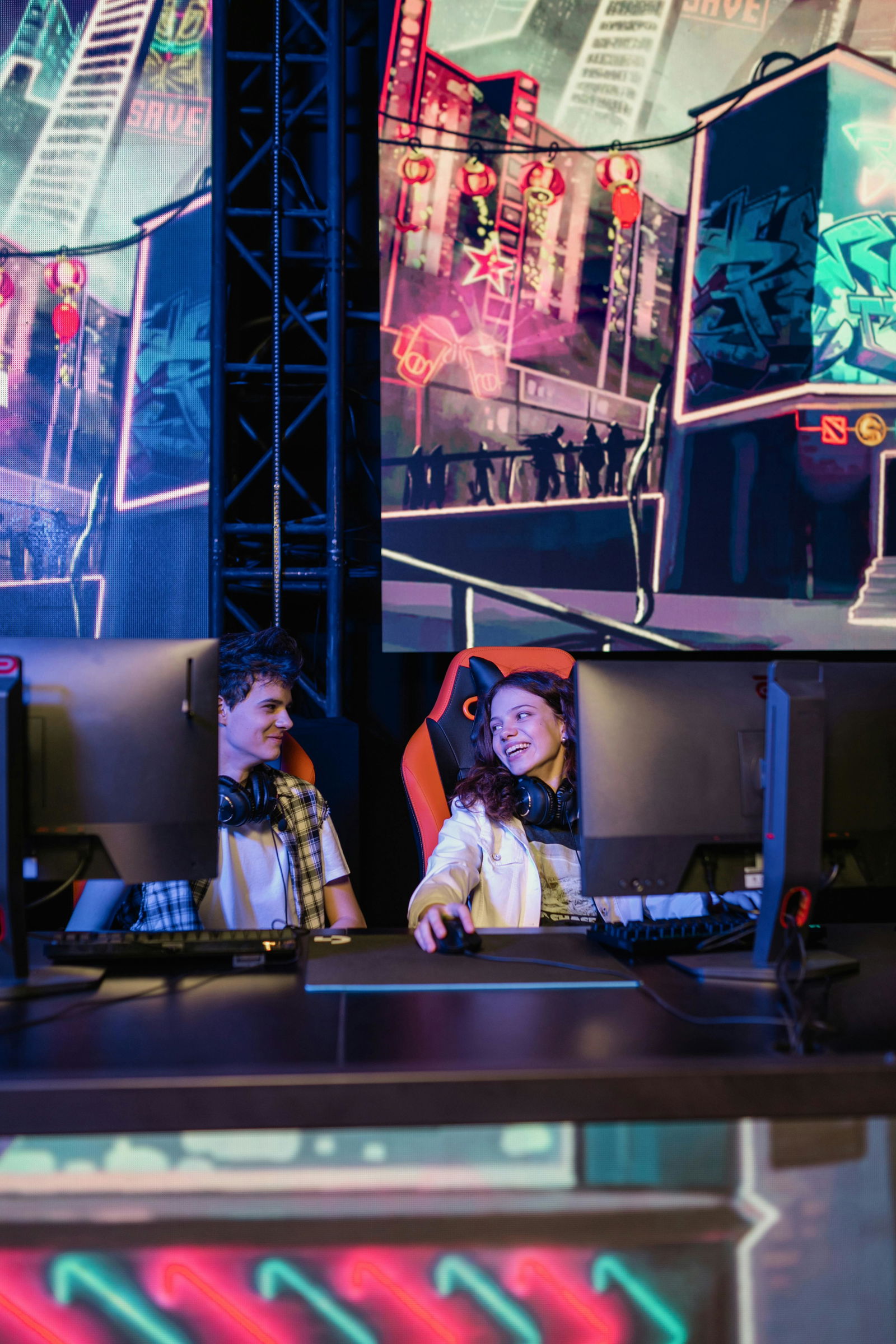 Zwei Gamer schauen sich lachend an und sitzen vor ihren Gaming-PCs