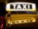 Ein beleuchtetes Taxi-Schild auf einem Autodach.