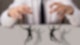 Ein Business-Mann in Hemd und Krawatte hat um seine Finger jeweils zwei Marionetten an Schnüren befestigt, die er wie ein Marionettenspieler tanzen lässt