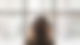 Frau mit Kopfhörern sitzt von einem großen Glasfenster
