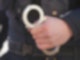 Ein Polizist hält Handschellen in der Hand.