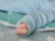 Ein wenige Wochen altes Baby ballt seine Hand zu einer kleinen Faust.