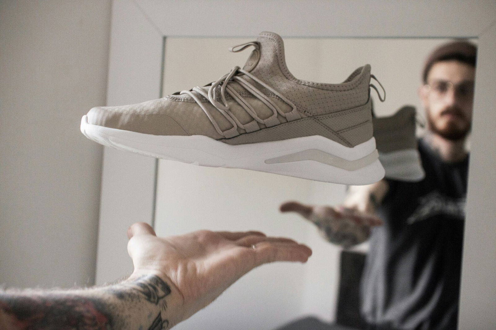 Mann steht mit Sneaker in der Hand vor einem Spiegel