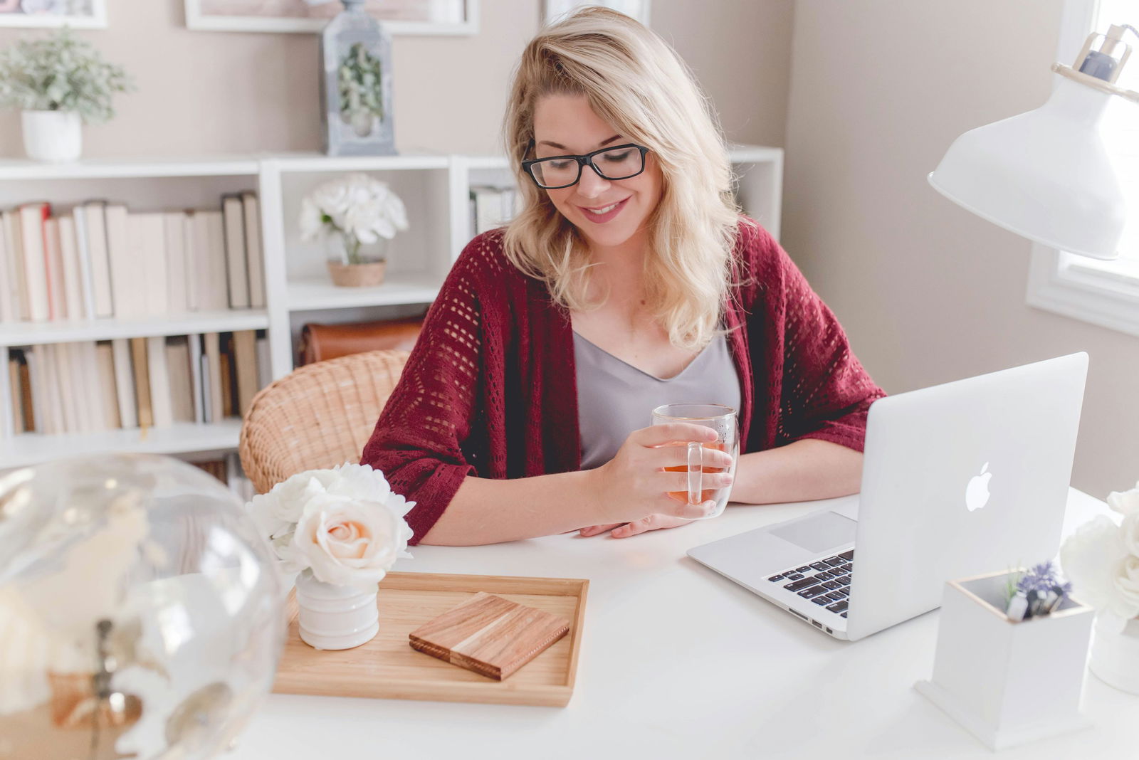 Frau am Schreibtisch mit Teetasse und Macbook