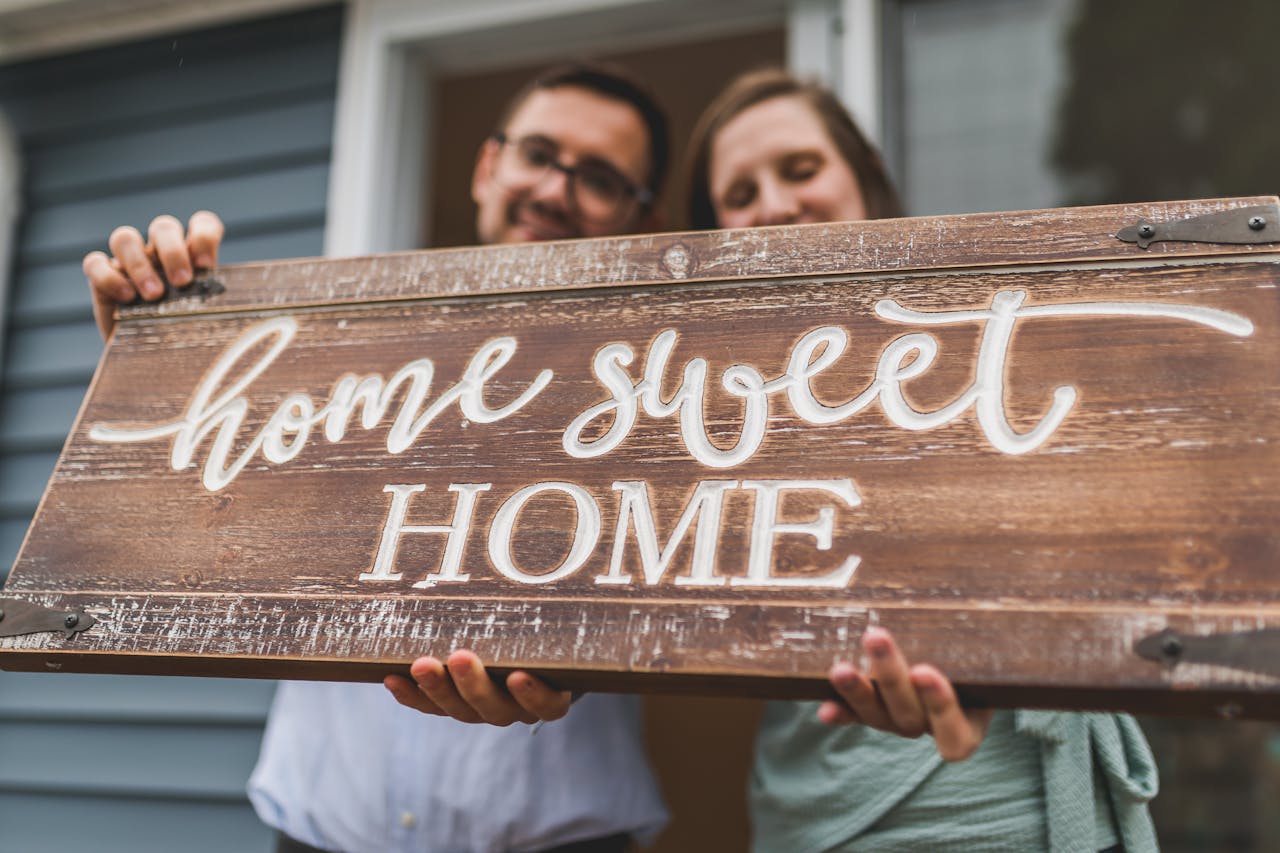 Junges Pärchen mit "Home Sweet Home" Schild aus Holz