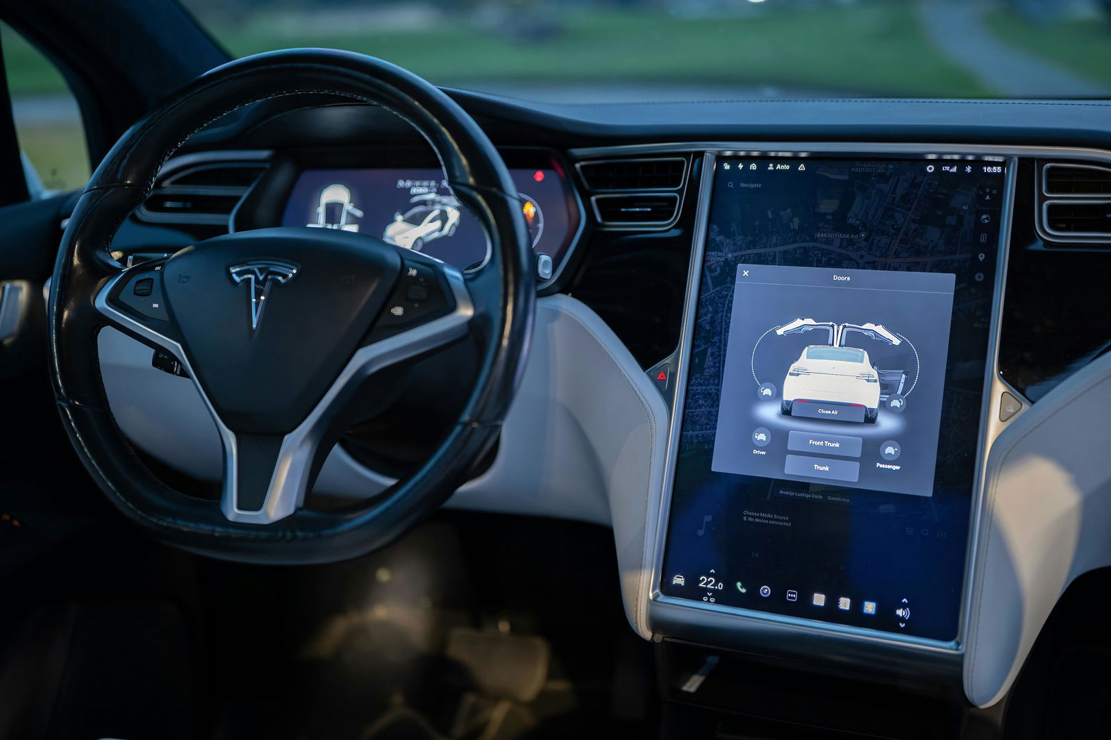 Ansicht eines Teslas von innen mit Blick auf das Board-Display und das Lenkrad 