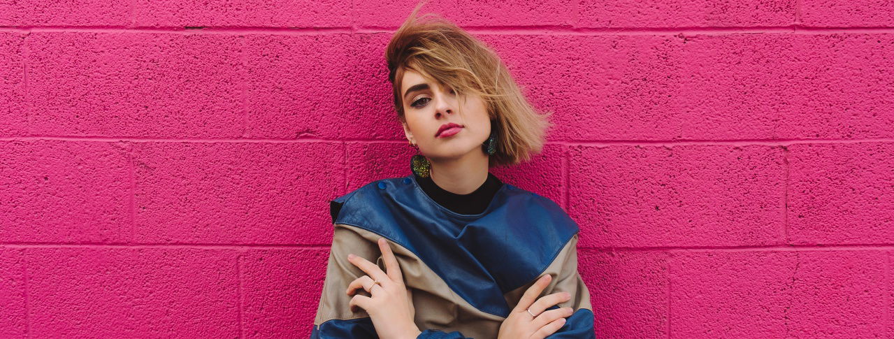 Frau steht mit verschränkten Armen an Wand 