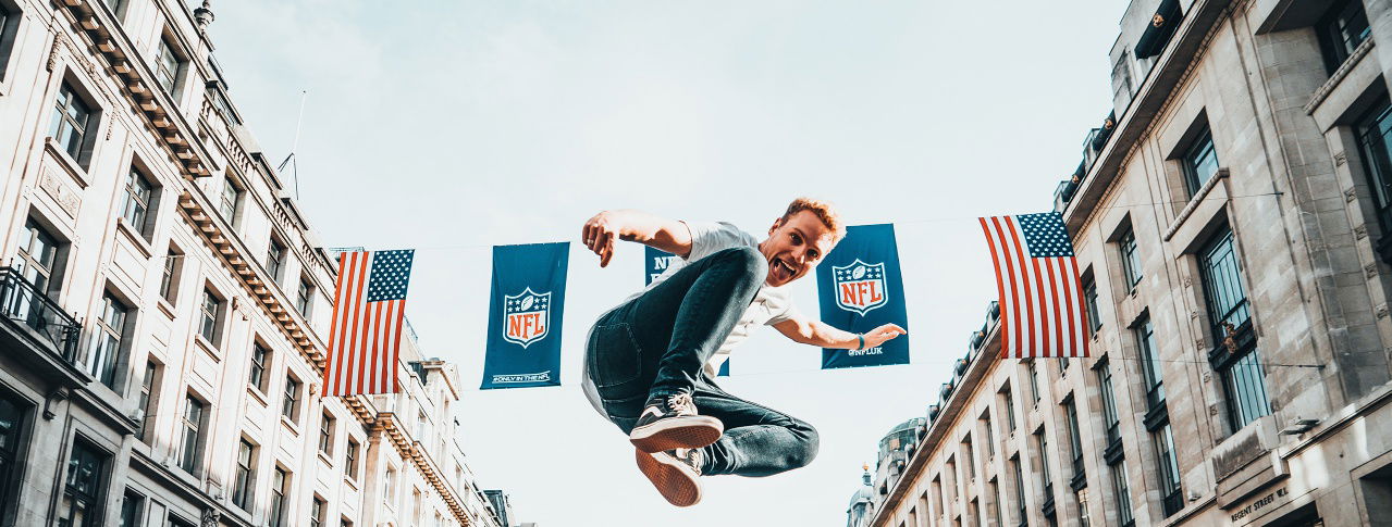 Mann springt in Luft vor amerikanischer Flagge