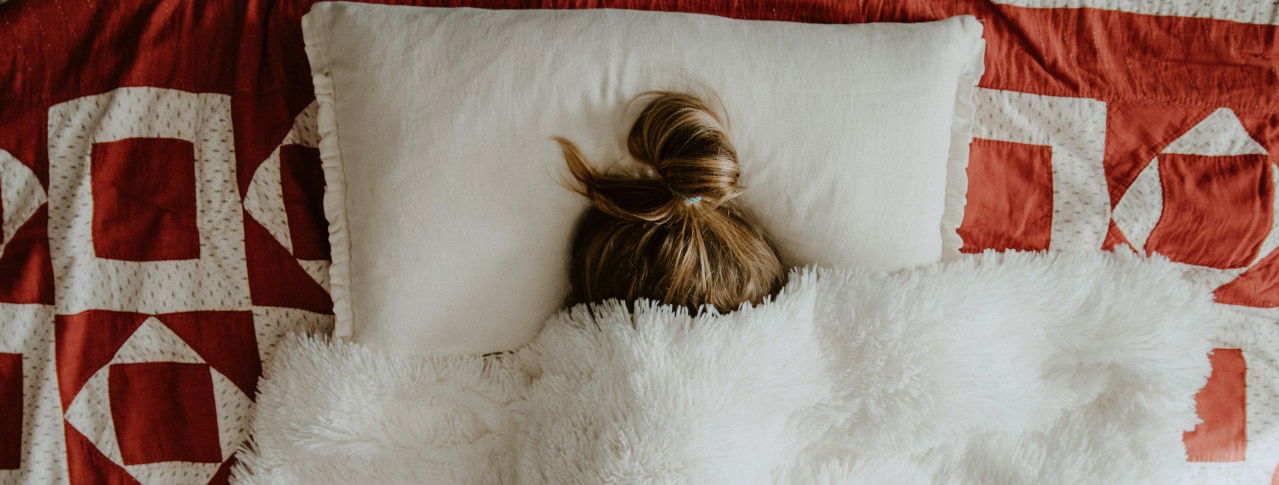 Frau versteckt sich in Bett unter Decke 