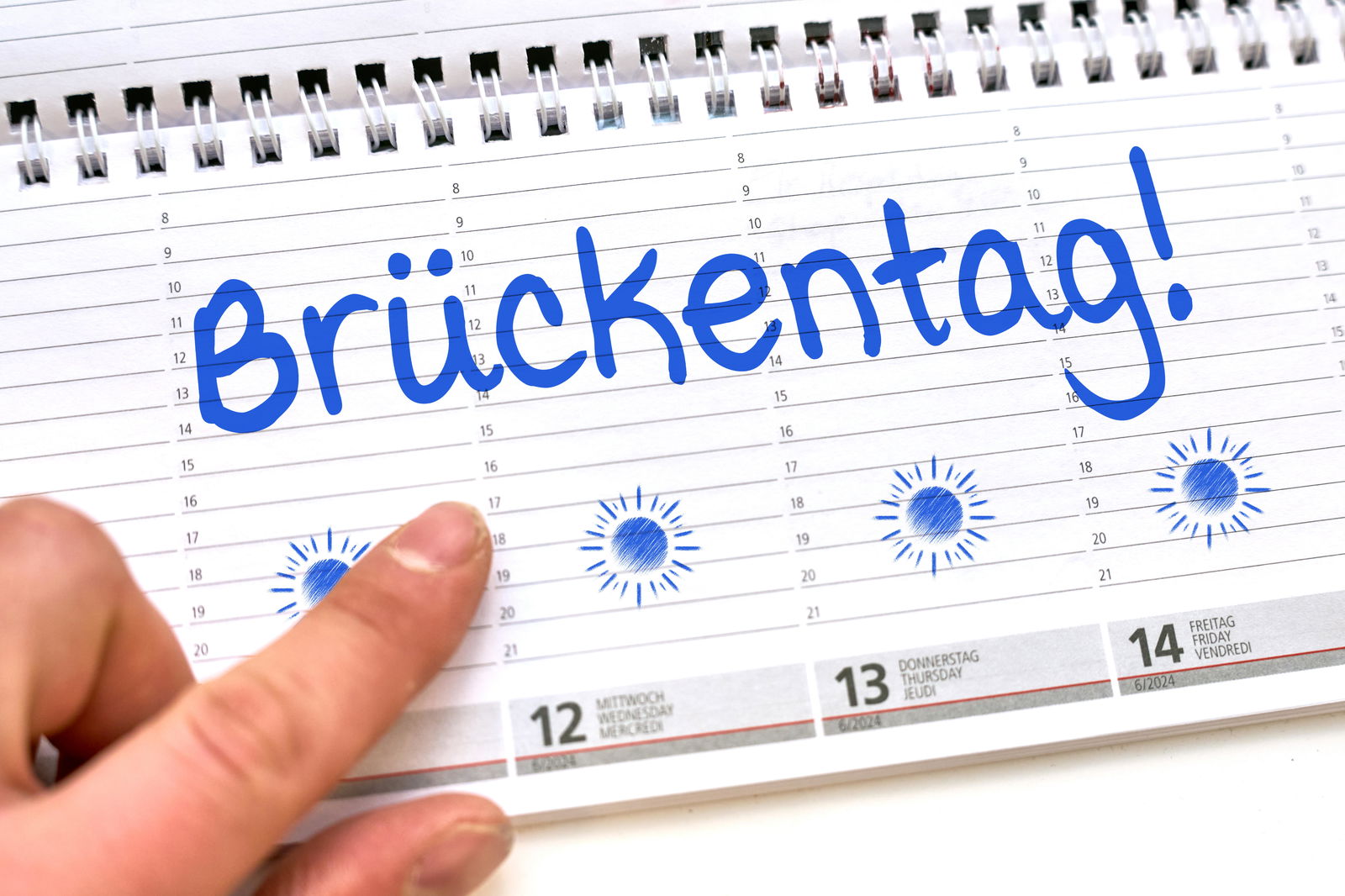 Finger zeigt auf ein Kalenderblatt mit Brückentag
