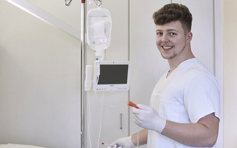 Junger Arzt lacht in Kamera