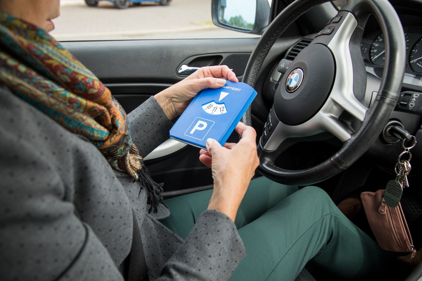 Frau stellt Parkscheibe im Auto ein