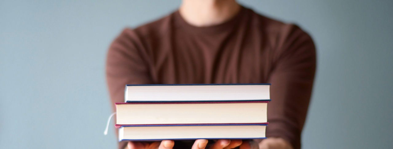 Person mit Bücherstapel in der Hand 