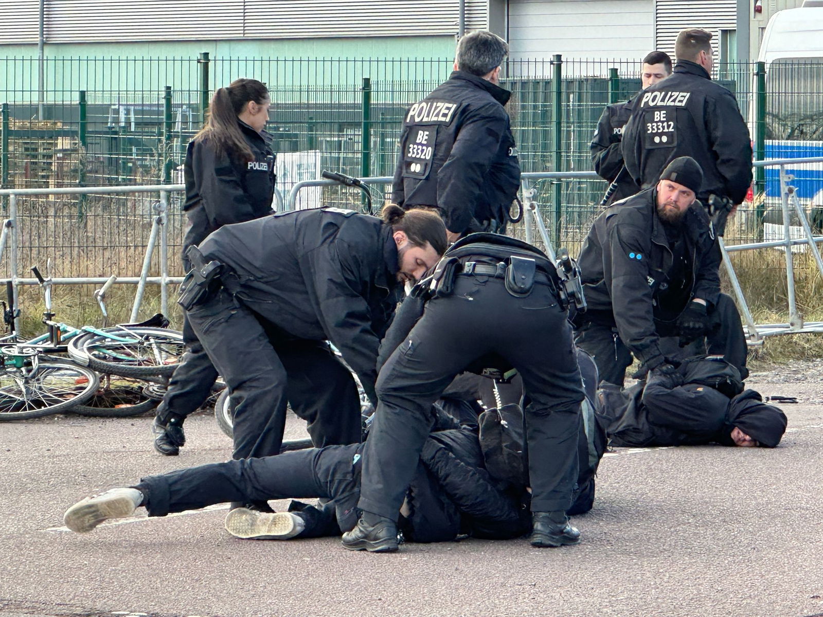 Polizisten halten Demonstranten am Boden fest. Sie hatten zuvor versucht mit Fahrrädern Richtung Veranstaltungshalle vorzudringen.