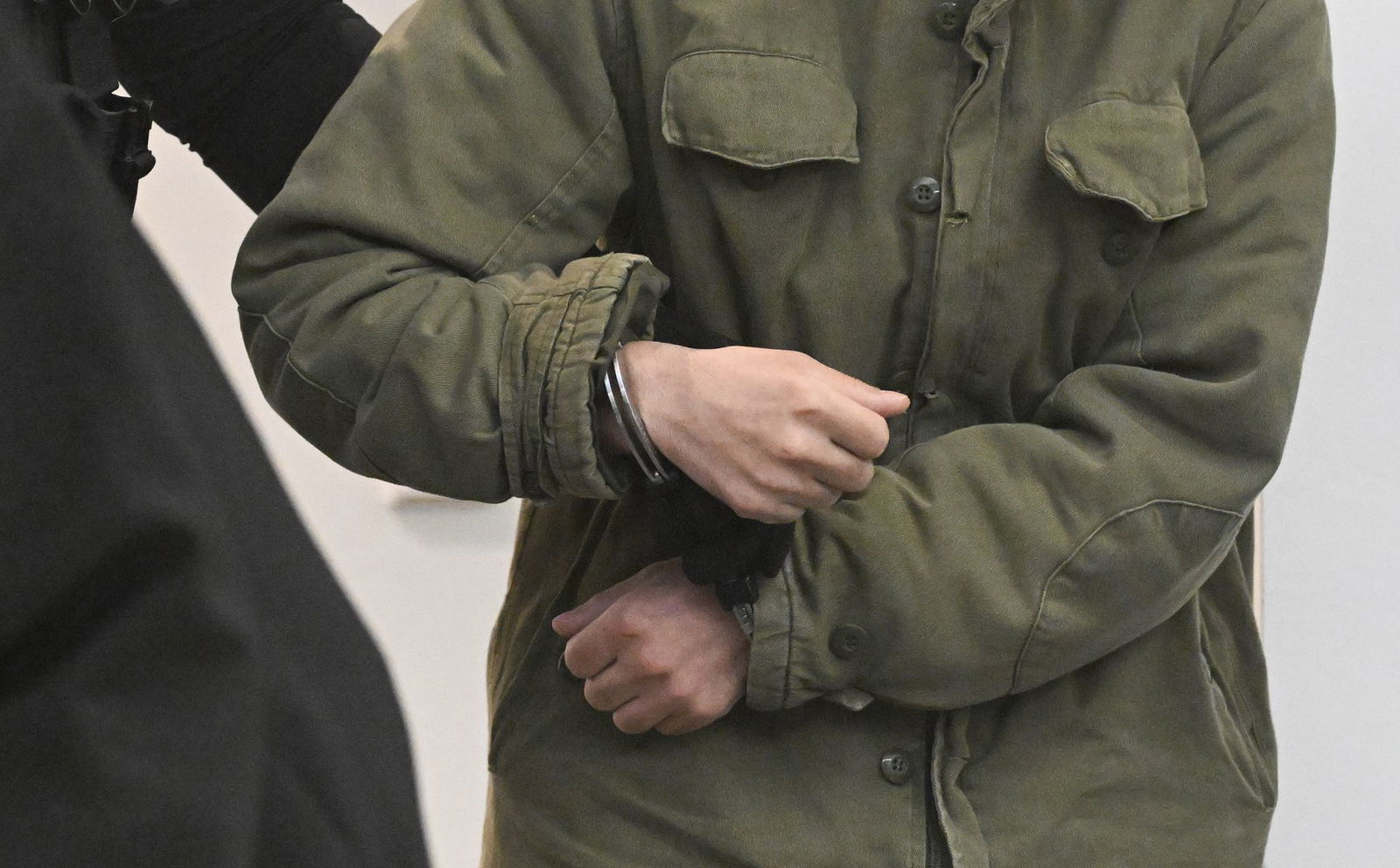 Der Angeklagte wird in Handschellen in einen Gerichtssaal im Oberlandesgericht Stuttgart geführt. 