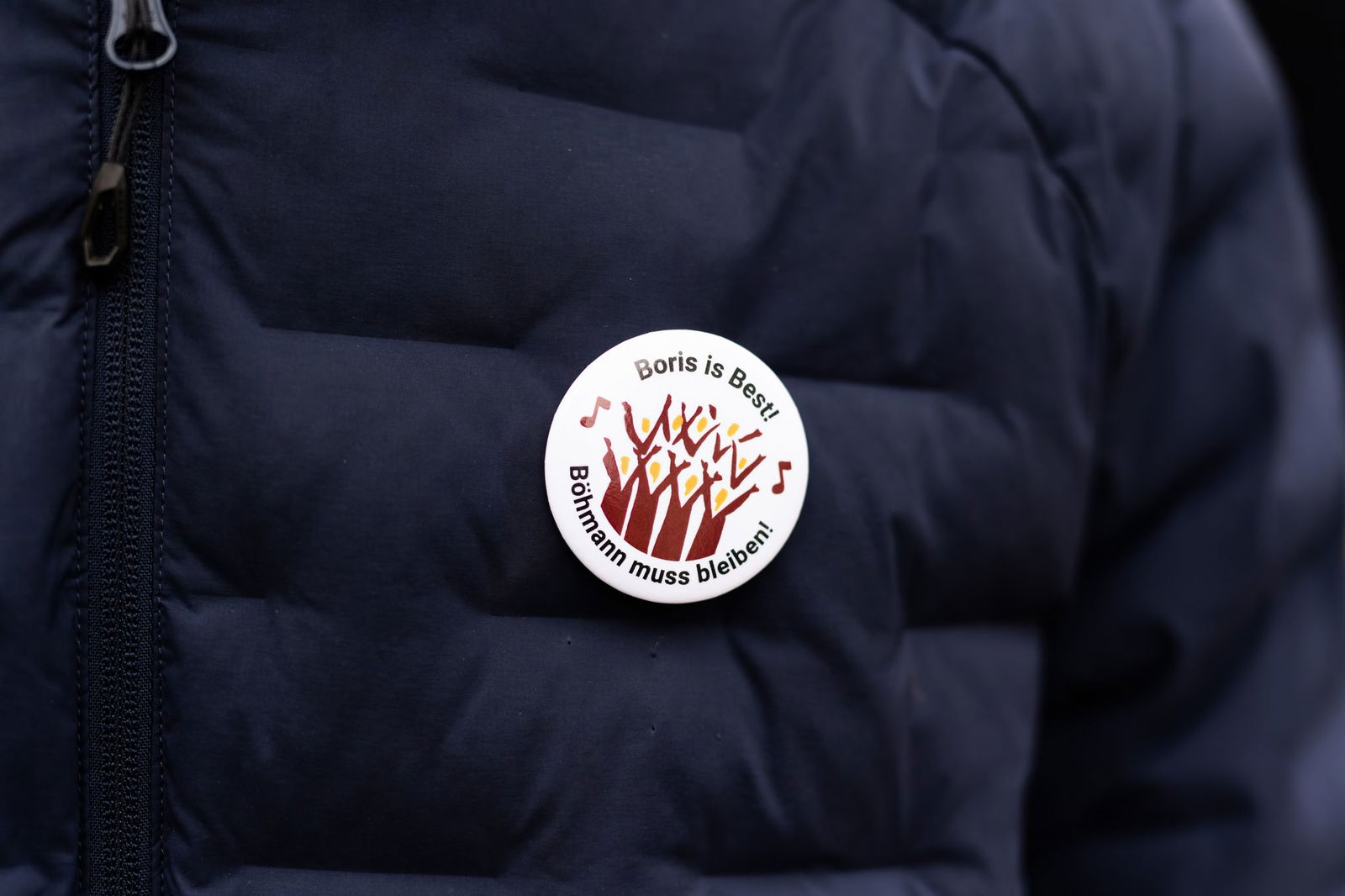 Ein Demonstrant trägt einen Button mit der Aufschrift «Boris is Best! Böhmann muss bleiben!». Viele Menschen in Freiburg stehen hinter Domkapellmeister Böhmann. (Archivbild)