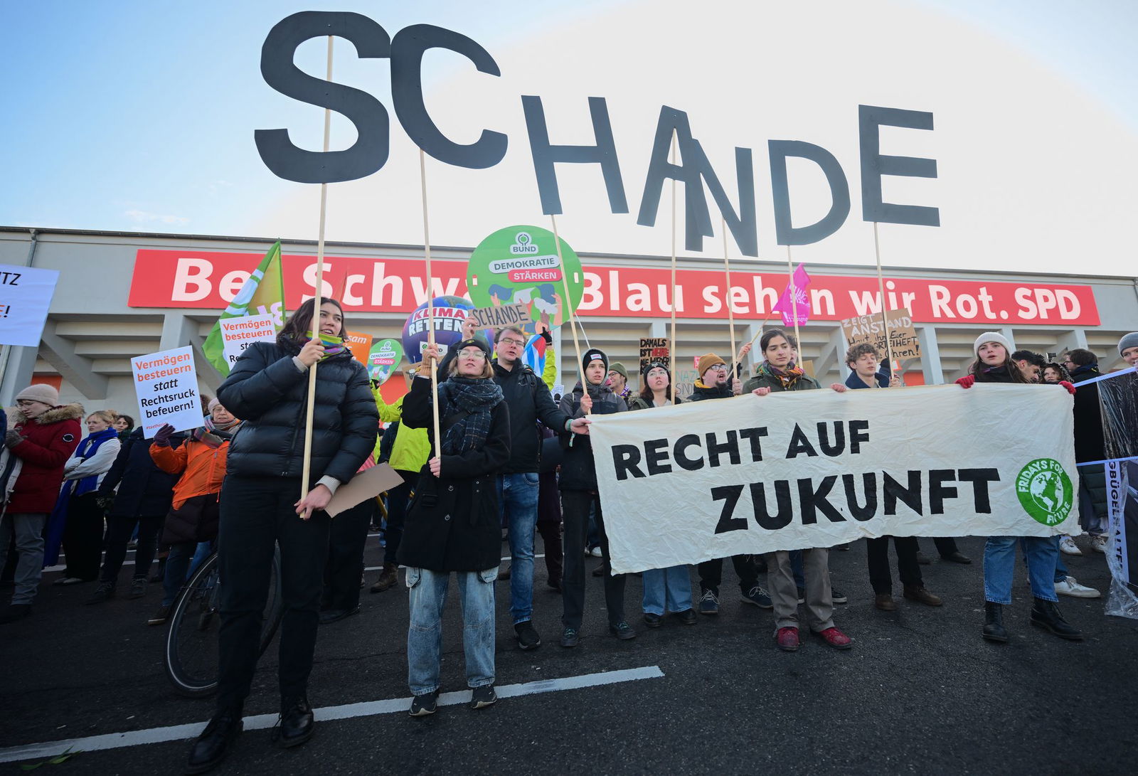 Zum Parteitag demonstrieren mehrere Menschen vor dem Gebäude. 