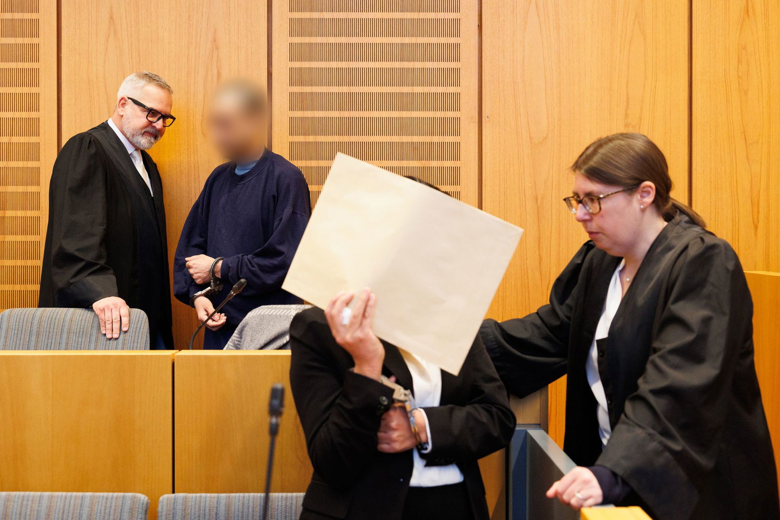 Die Mutter kam mit einem großen Briefkuvert vor dem Gesicht in den Gerichtssaal, der Vater trug einen Pullover der Justizvollzugsanstalt Frankenthal.