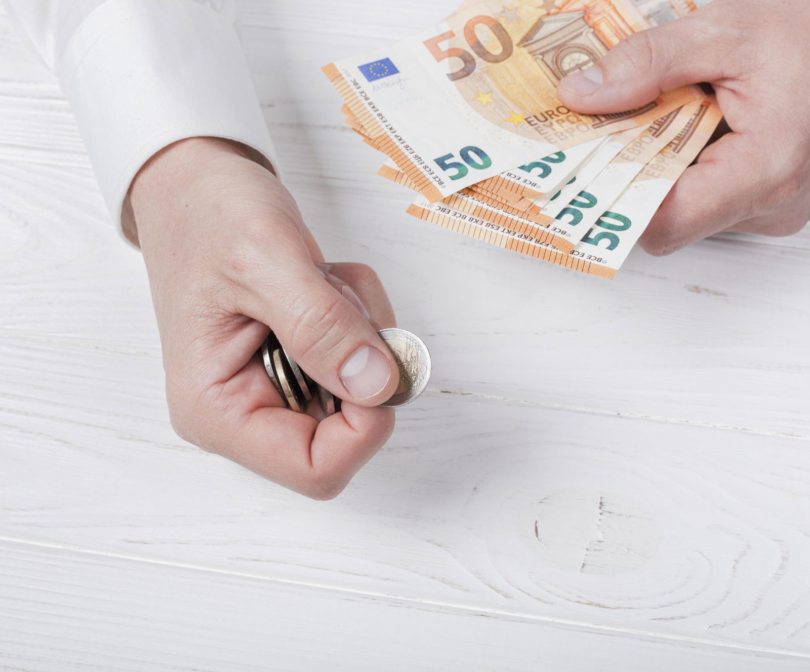 Eine Hand hält Geldscheine und Münzen